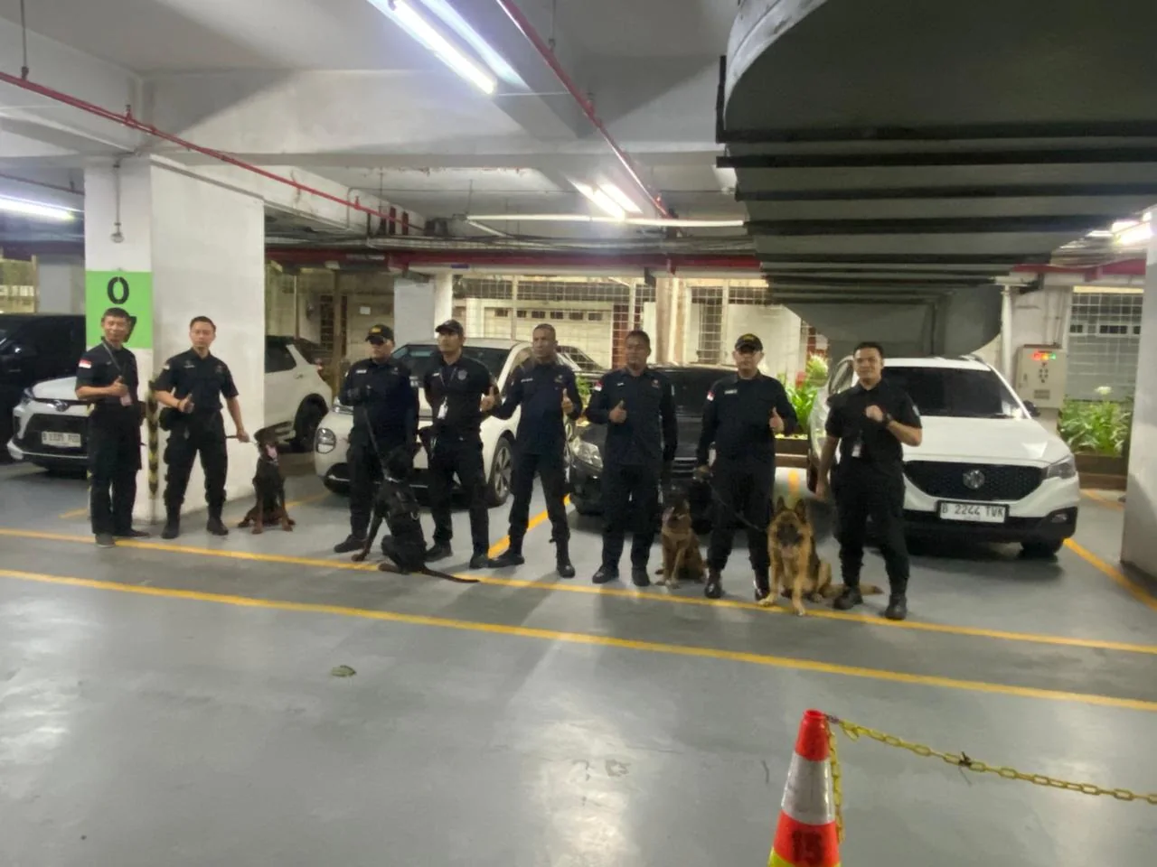 Personel dan handler bersama unit K9 di area parkir.