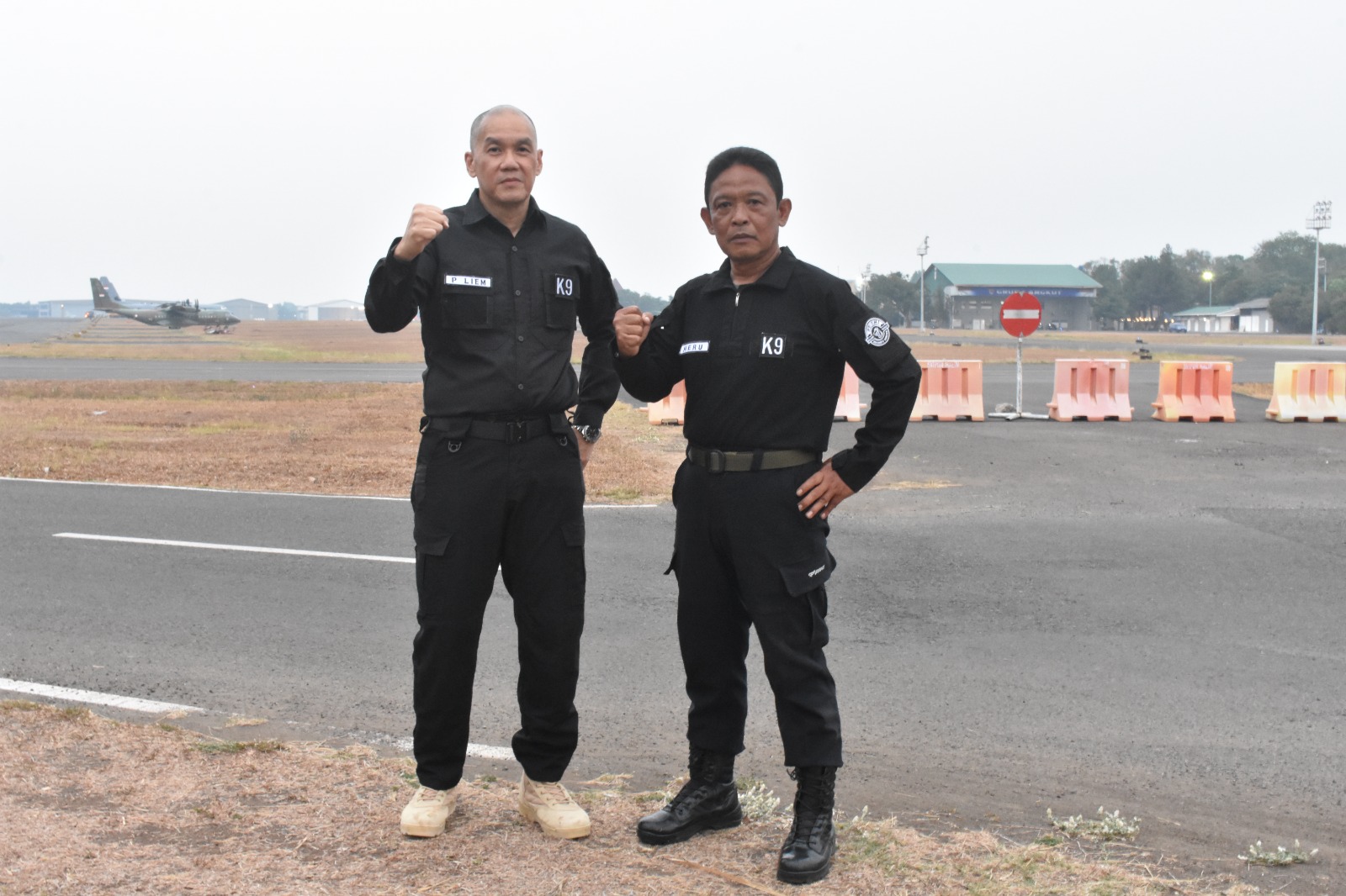 Dua personel K9 berpose di landasan pacu pesawat.